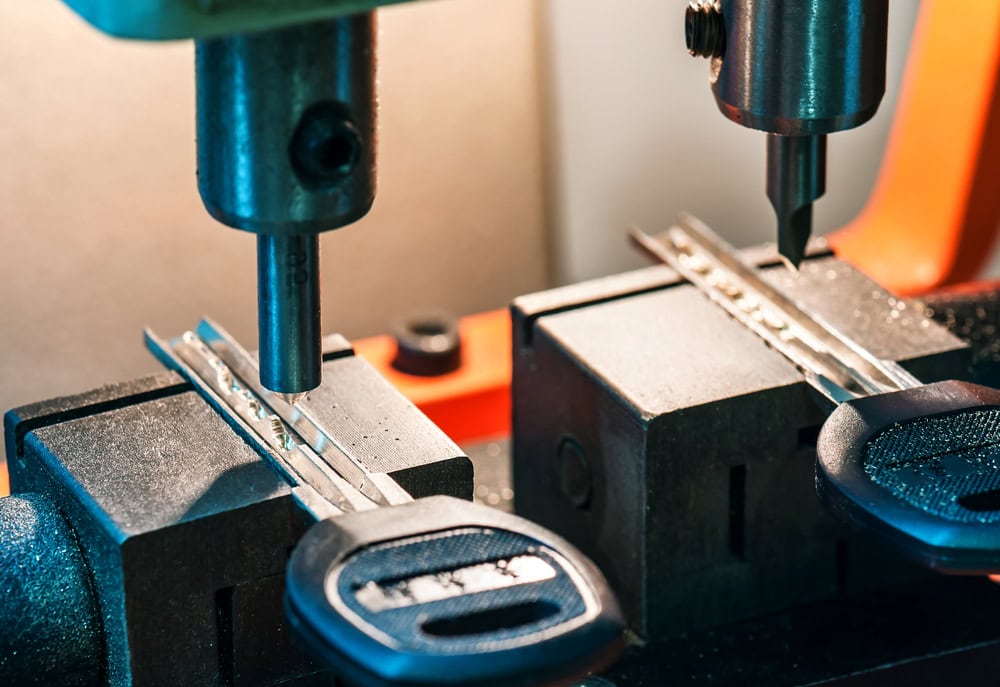 Close-up of a key cutting machine in operation at a PA locksmith, with two metal keys being shaped by automated cutting tools—showcasing expert Locksmith Services Delaware County relies on.