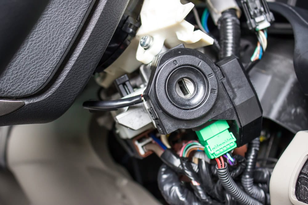 Close-up view of a car ignition switch with the key slot exposed, surrounded by electrical wiring and connectors under the steering column—ideal for PA Locksmith Services Delaware County assistance.