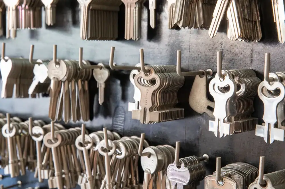 Rows of various blank metal keys hang on hooks against a wall, organized in bunches, ready to be cut and used for locks.